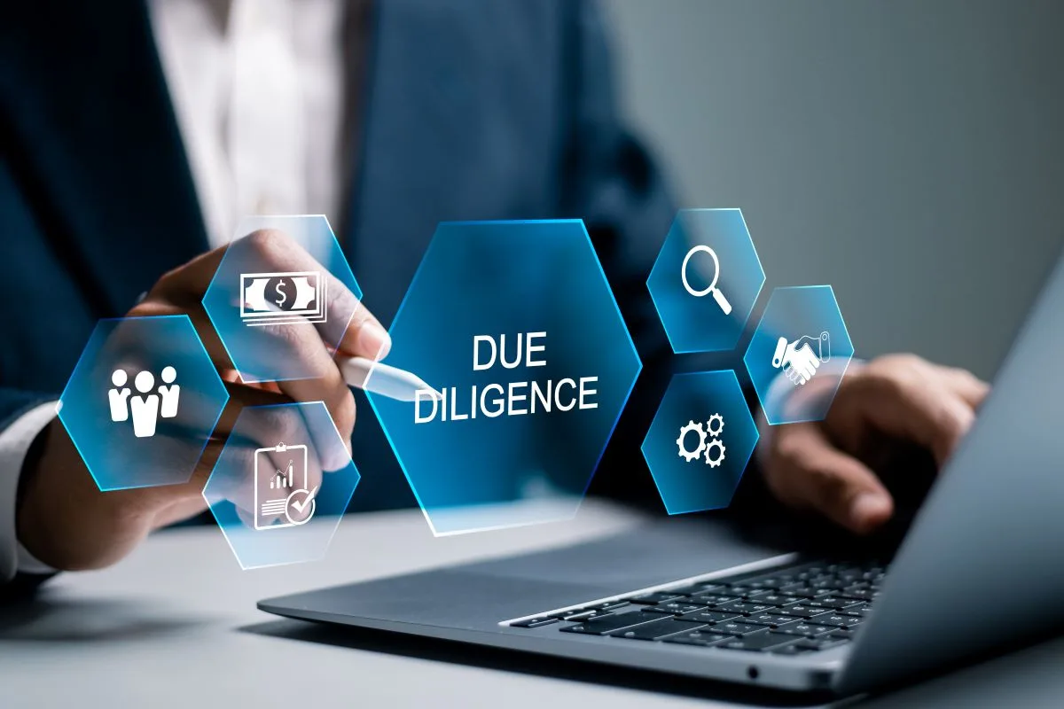 Businessman using laptop with a due diligence icon on a virtual screen.